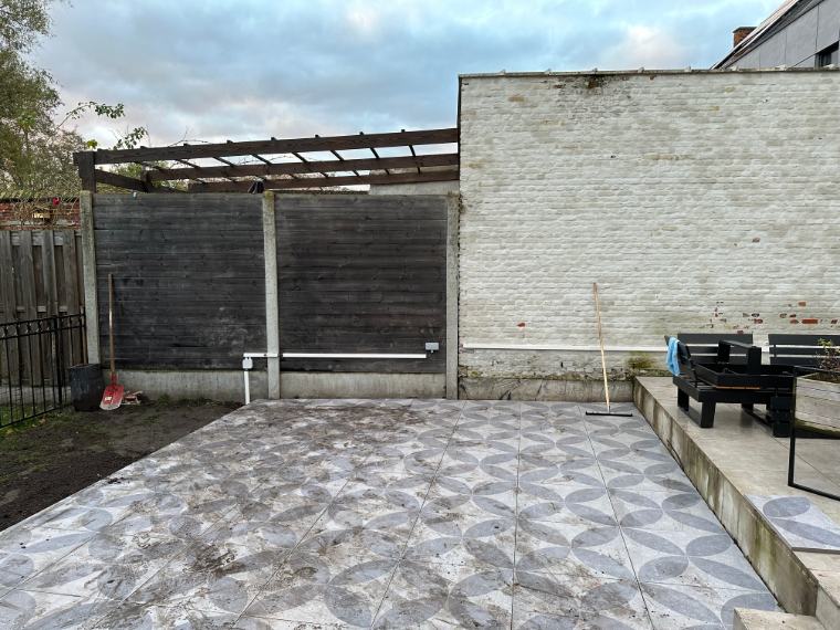 Montage van het leidingwerk en de verdelerdozen langs de wand en schutting. De bekabeling is strak en netjes weggewerkt, klaar om de armaturen van stroom te voorzien zonder afbreuk te doen aan de esthetiek van de tuin.